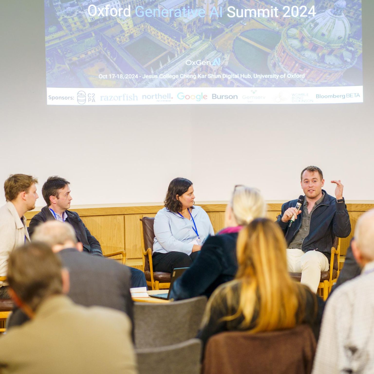 Joseph speaking into a microphone during a panel discussion at the Oxford Generative AI Summit.